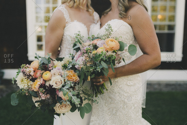 Newlywed brides posed with bouquets together after wedding