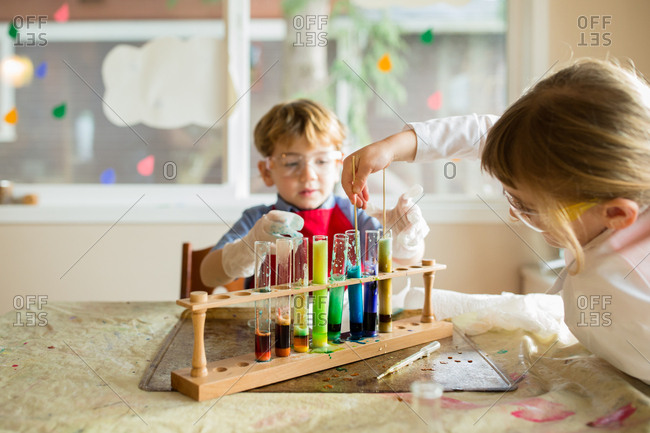 Studious siblings playing with chemistry set at the dining room table