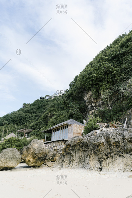 Beach hut built on rocks at foot of cliff in Bali, Indonesia