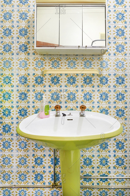 Bathroom interior with lime green pedestal sink and flowery tiles