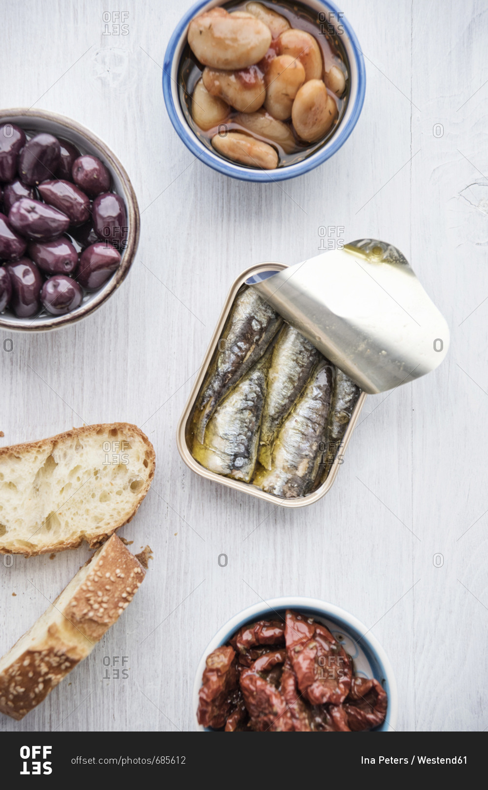 Tin can of sardines in oil- bowls of pickled vegetables and slices of bread