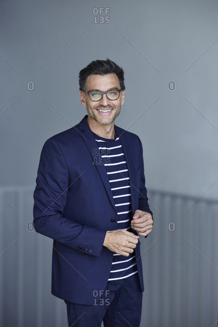 Portrait of smiling businessman with stubble wearing blue suit and glasses