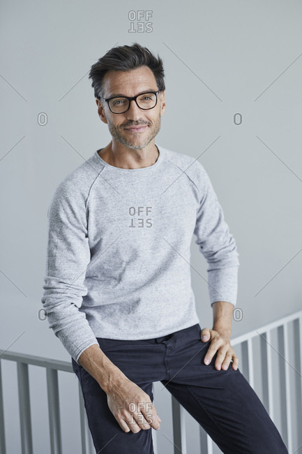 Portrait of smiling man with stubble wearing grey sweatshirt and glasses