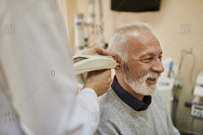 ENT physician examining ear of a senior man