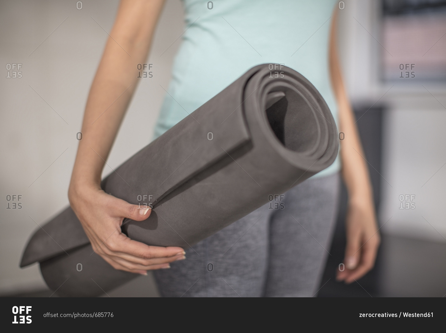 Close-up of woman carrying yoga mat in studio