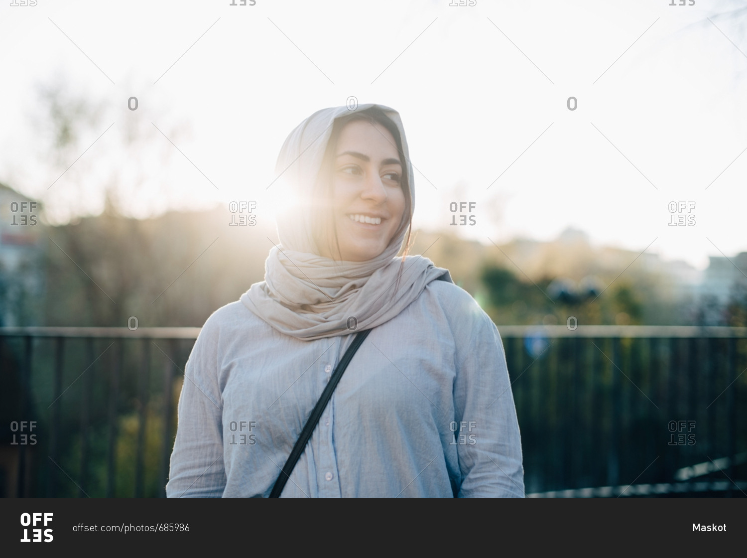 Back lit of smiling young Muslim woman wearing hijab against sky