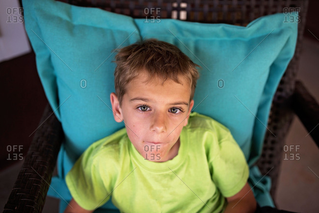 Portrait of young boy sitting in whicker chair outdoors