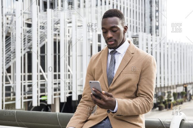 Young black professional checking phone in the city