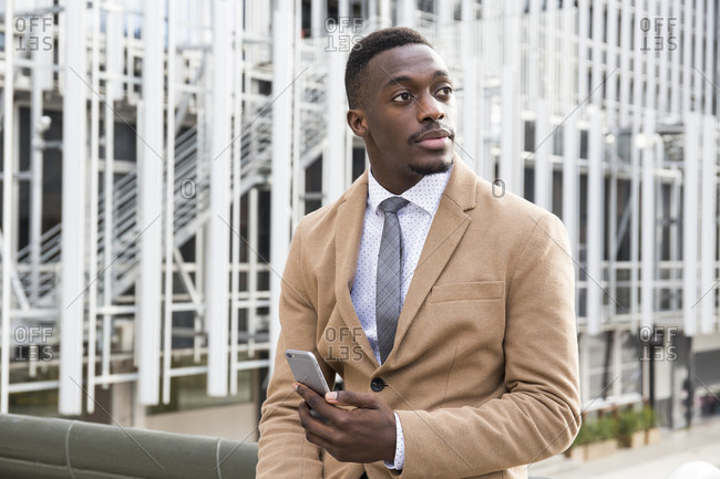 Black Madrid businessman looking up from phone outside