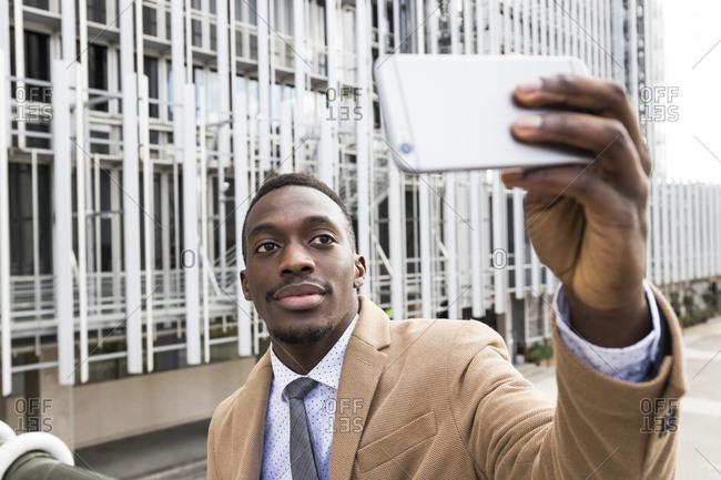 Black man in a suit taking a selfie photo with his smartphone