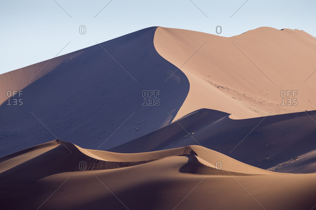 Africa, Namibia, Namib Naukluft National Park, Morning sun lights windblown red sand dunes in Namib Desert near Sossusvlei