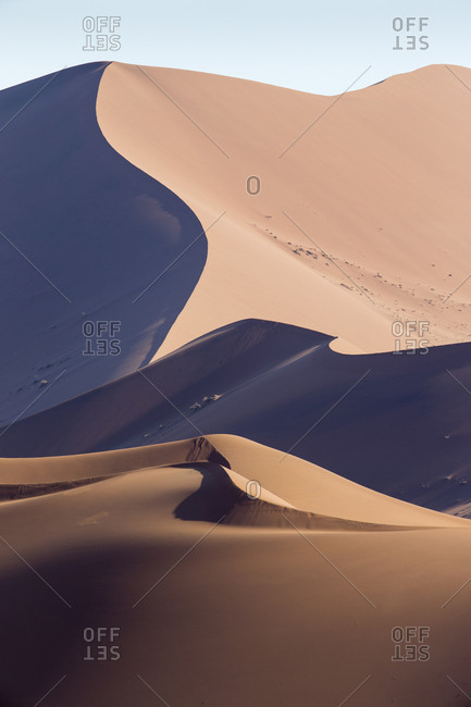 Africa, Namibia, Namib Naukluft National Park, Morning sun lights windblown red sand dunes in Namib Desert near Sossusvlei