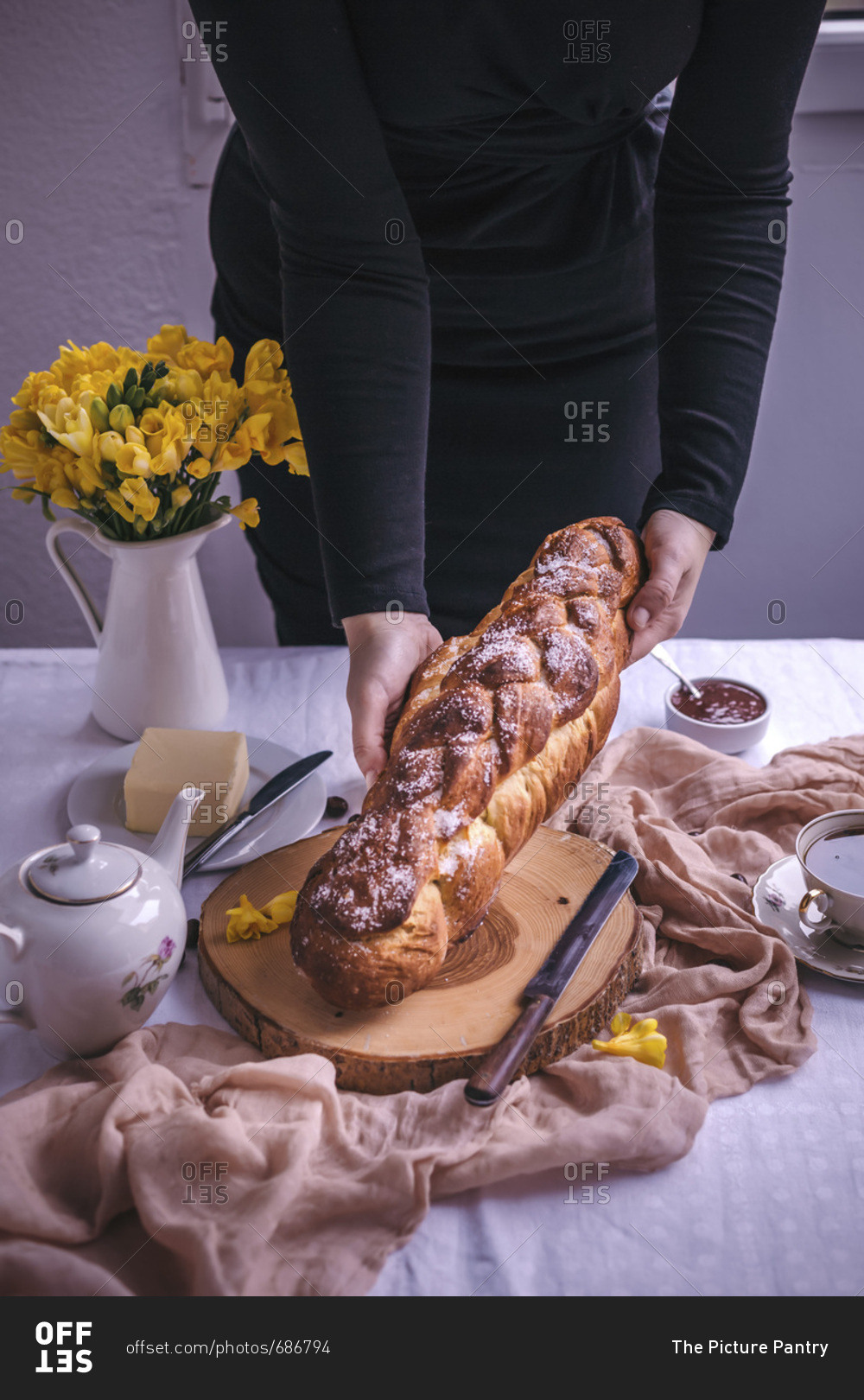 Woman holding a braided sweet Easter bread served for breakfast with butter and jam