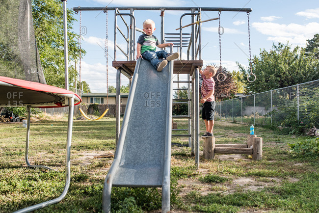 Brothers playing on swing set in backyard