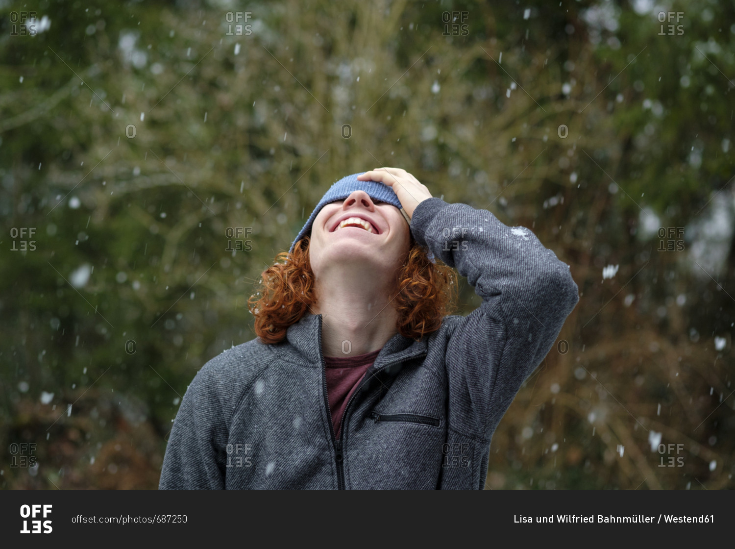 Happy teenage boy enjoying snowfall stock photo - OFFSET