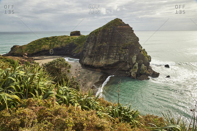 The surfers' paradise and volcanic black sand beach at Piha, showing Lion Rock, a monolith housing many Maori carvings, Auckland area, North Island, New Zealand, Pacific
