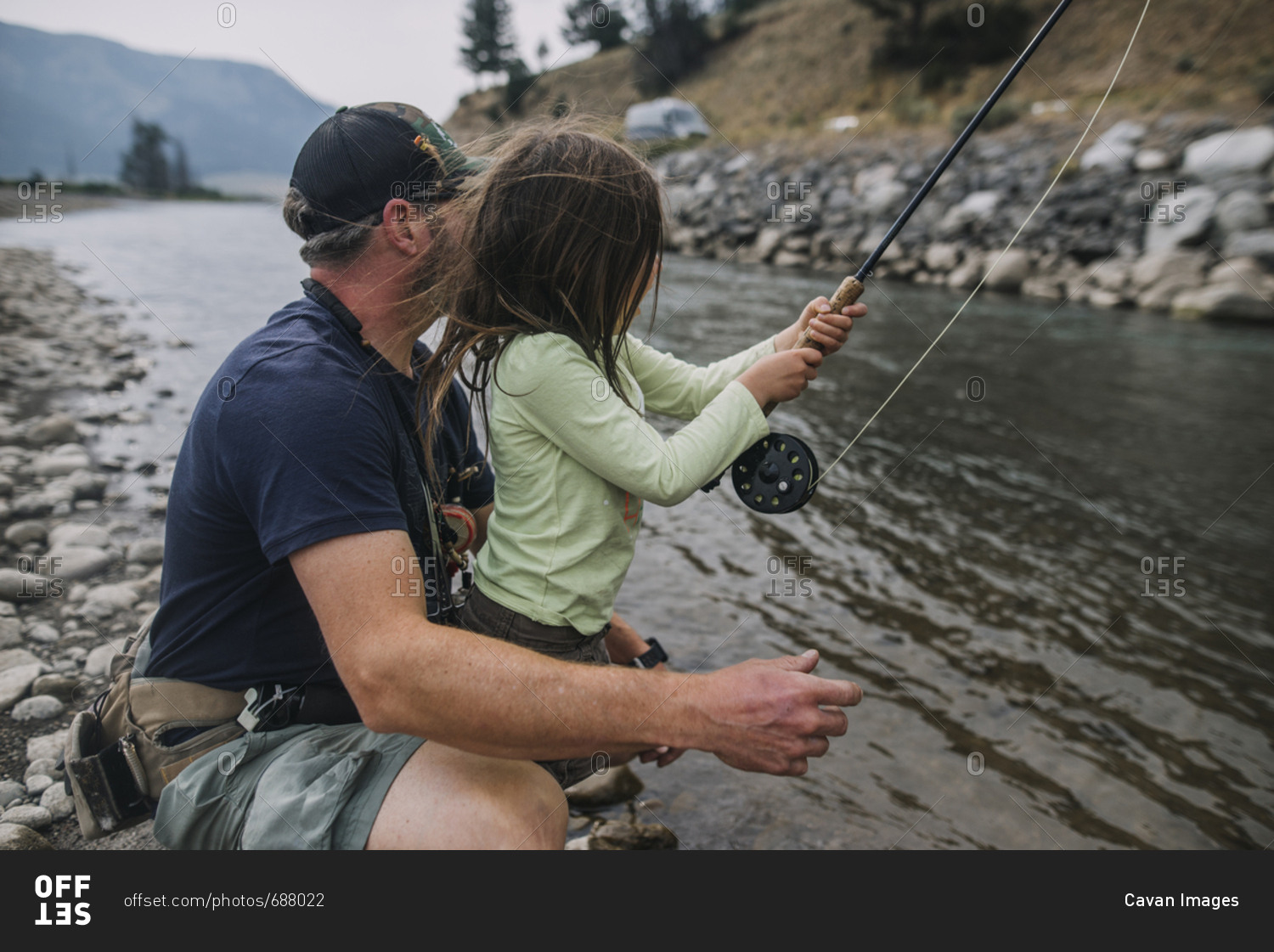 Side view of father and daughter fishing in river at Yellowstone National Park