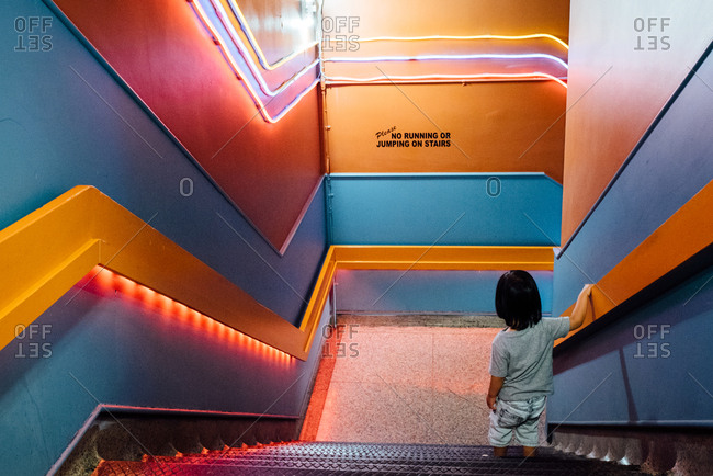 Toddler going down stairwell with colorful walls