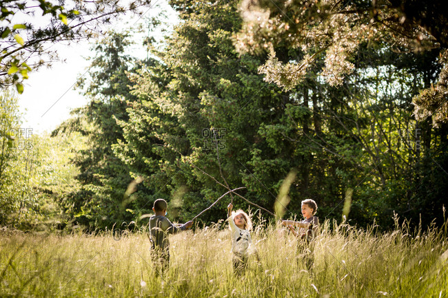 Kids playing with sticks in a field