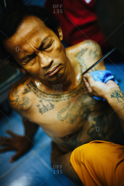 March 19, 2011: Portrait of Thai man getting "sak yant" traditional hand poked magic tattoo during Wai Khru festival in Wat Bang Phra, Thailand