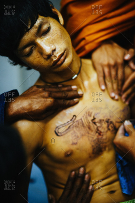 March 19, 2011: Young man getting "sak yant" traditional hand poked magic tattoo during Wai Khru festival in Wat Bang Phra, Thailand