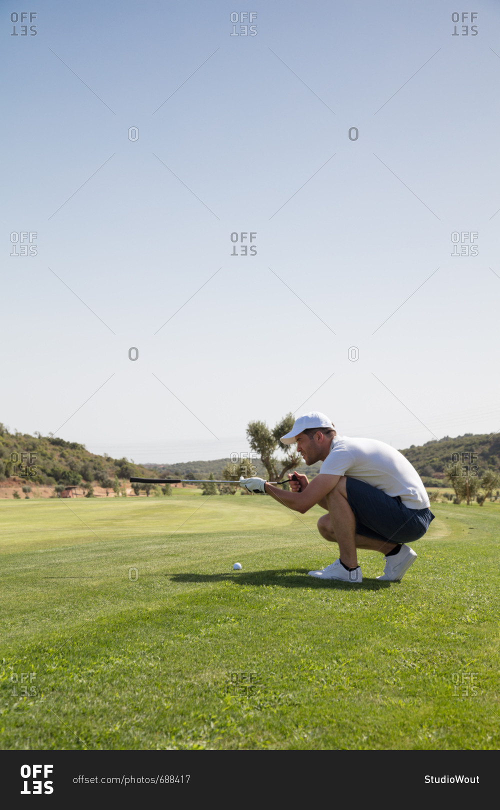 Golf player measuring stroke angle with golf club