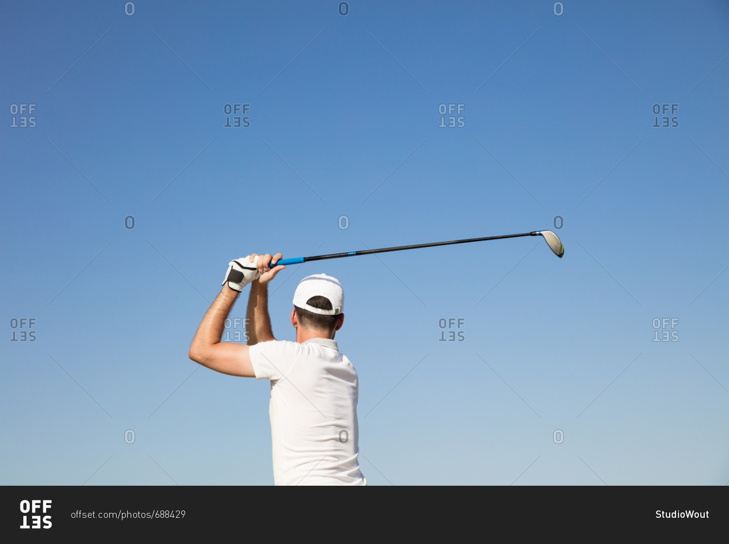 Golf: Male golfer after swing against blue sky