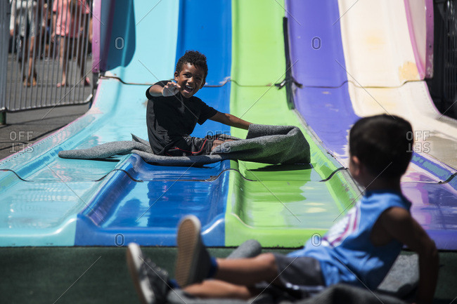 Little brother watching big brother descend large park slide