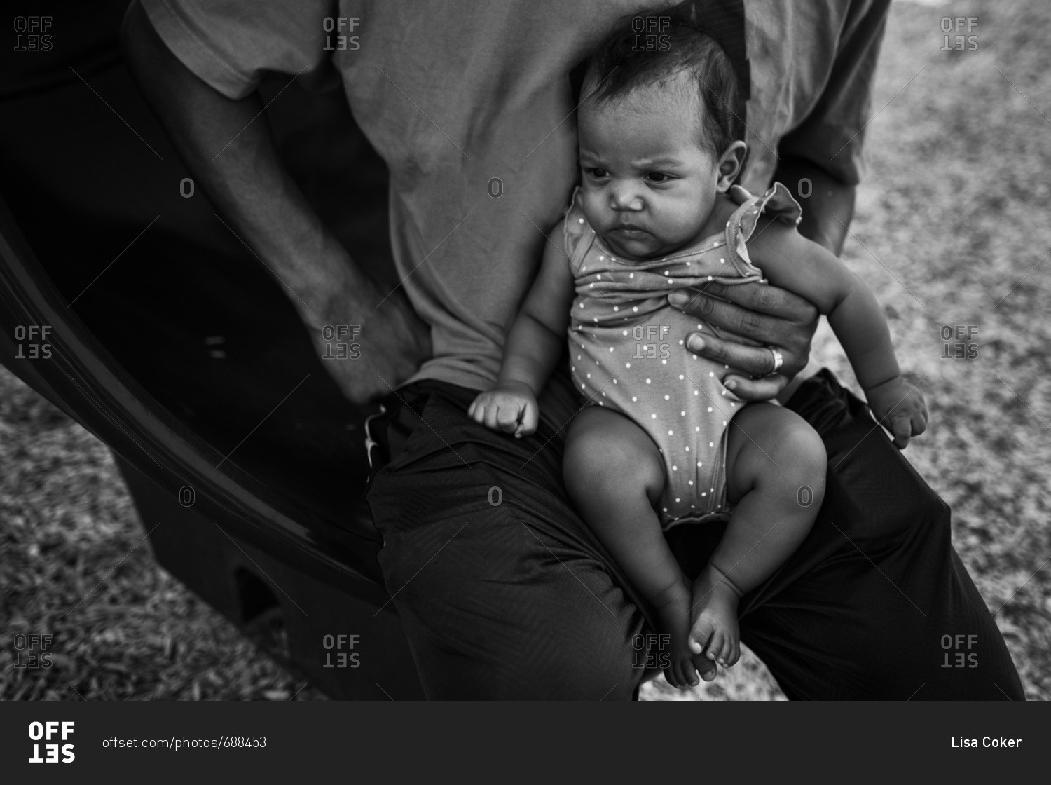 Black and white family portrait of concerned baby in father\'s lap