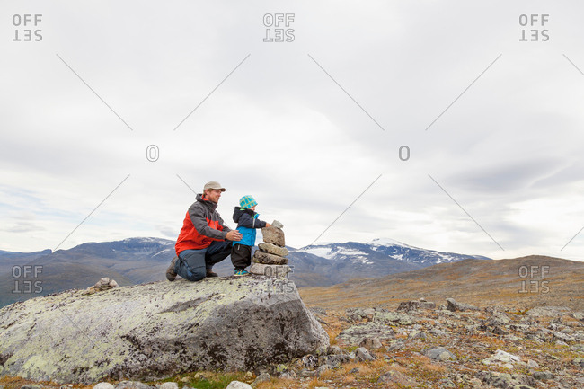 Male hiker with son building cairn in mountain landscape, Jotunheimen National Park, Lom, Oppland, Norway