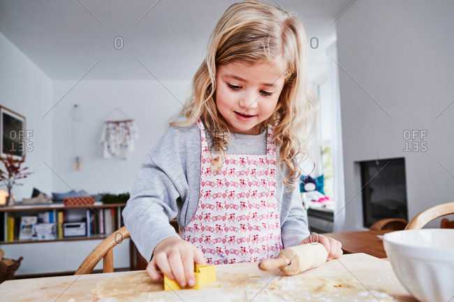 Young girl making cookies, using cookie cutter