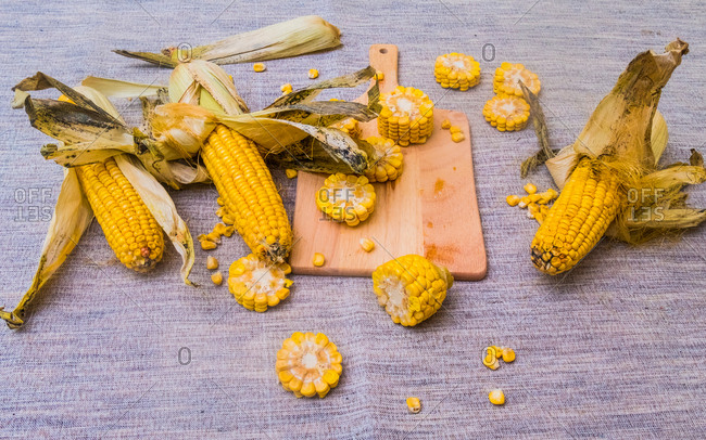 Sliced corn on the cob on chopping board, with whole corn on cob