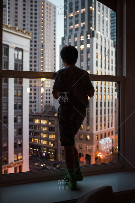 Man looking through window at cityscape stock photo - OFFSET