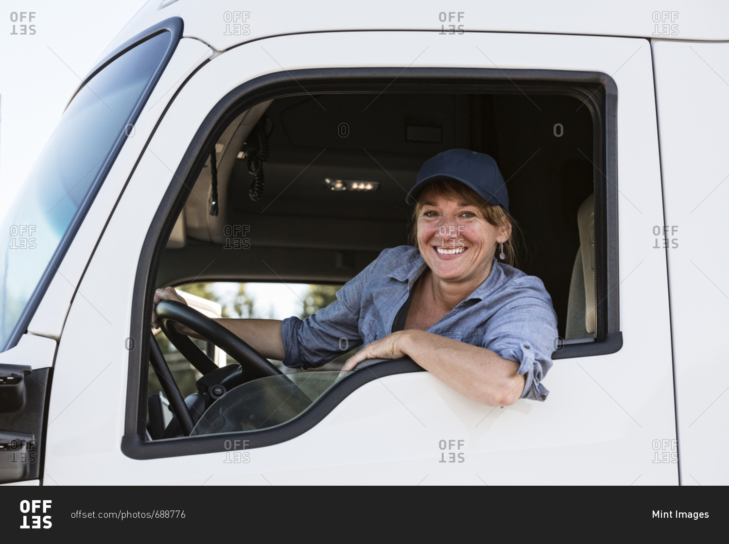Caucasian woman truck driver in the cab of her commercial truck at a truck stop