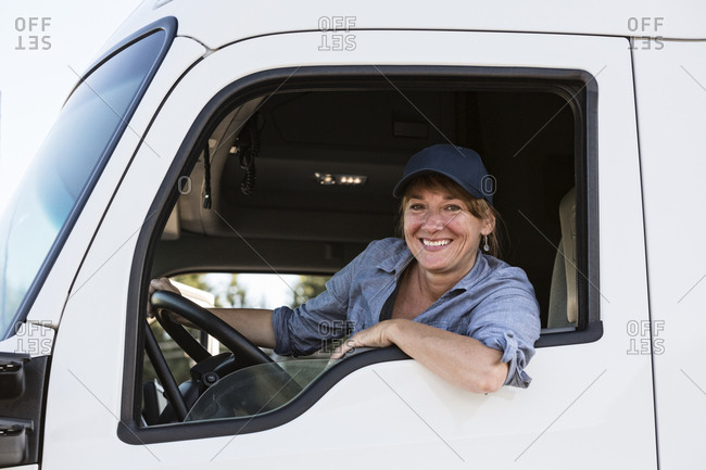 Caucasian woman truck driver in the cab of her commercial truck at a truck stop