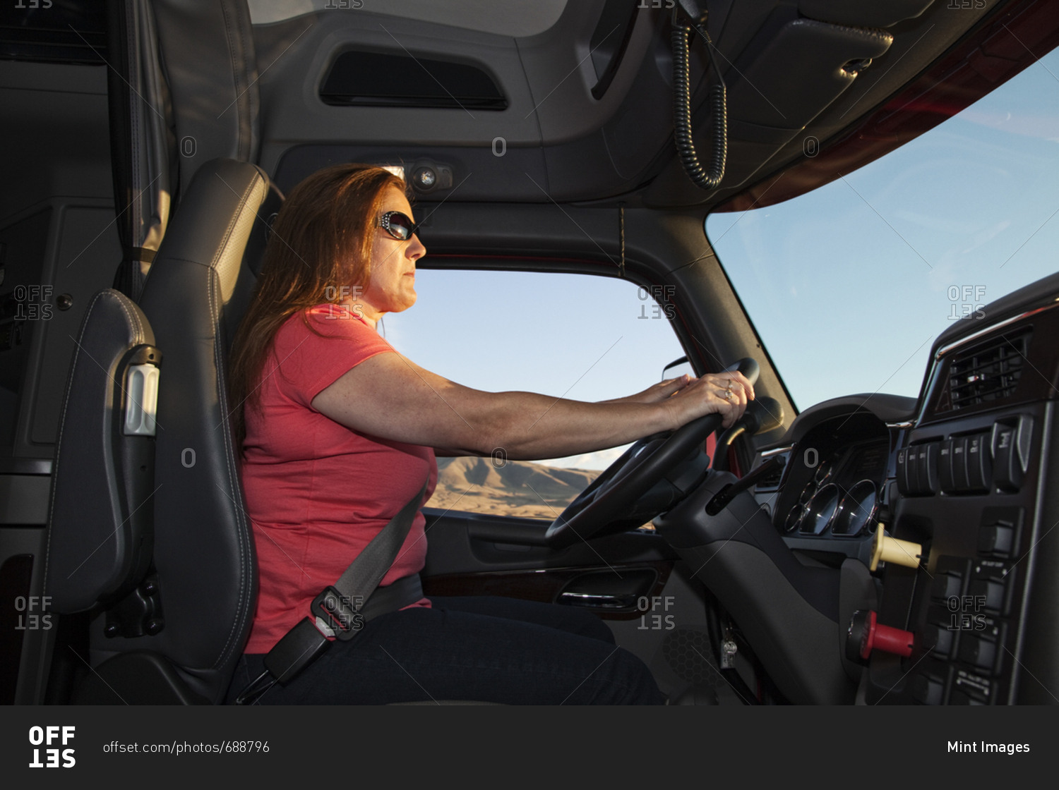 Interior cab view of a Caucasian woman driver driving her  commercial truck
