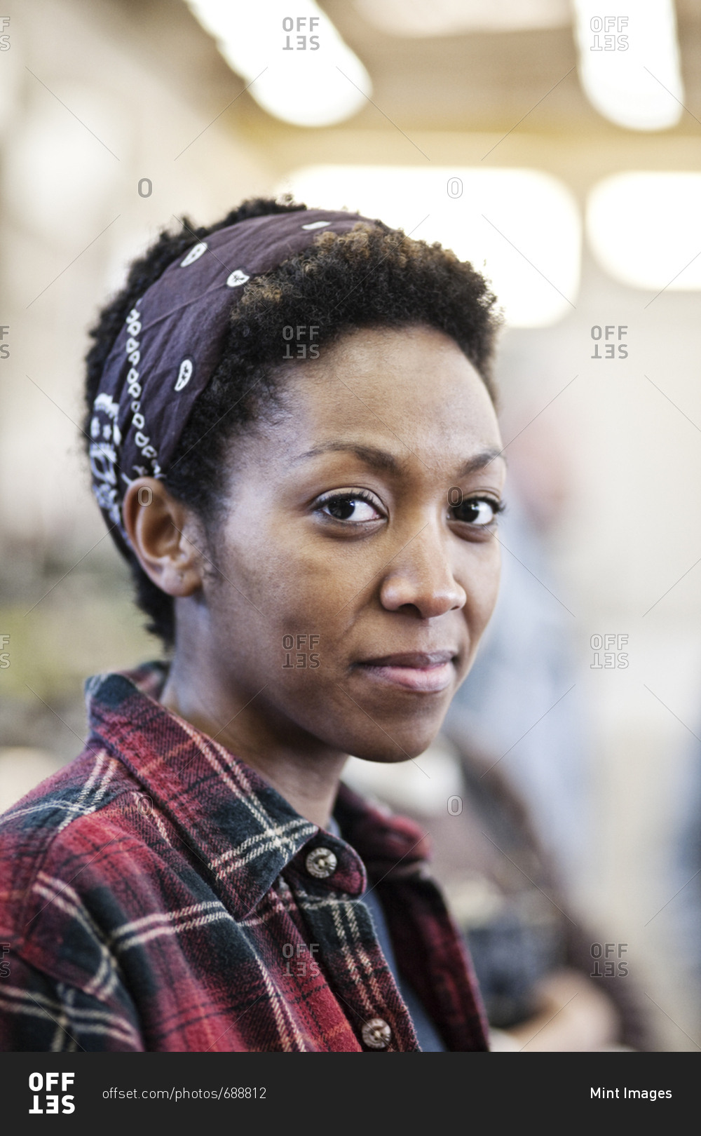 Black woman wearing a bandana in a factory stock photo - OFFSET