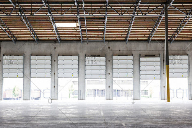 Wide angle interior view of large empty warehouse and loading dock doors