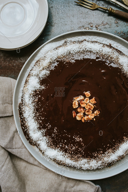 Overhead shot of delicious chocolate cake with coconut flour on chocolate glaze and hazelnuts in the middle