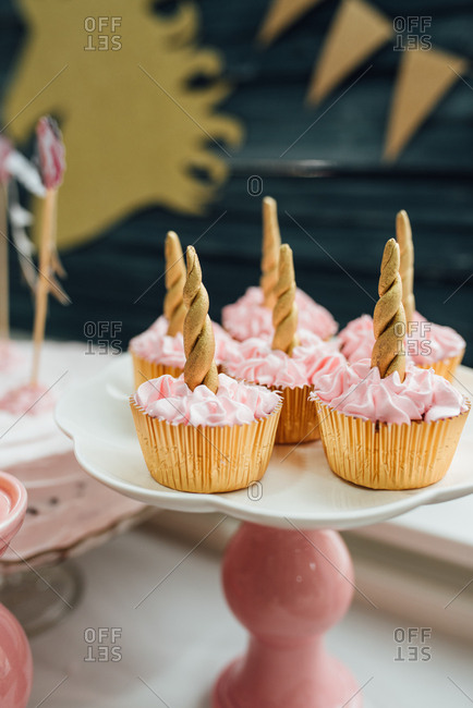 Cupcakes in gold wrappers with gold unicorn horn and pink cream