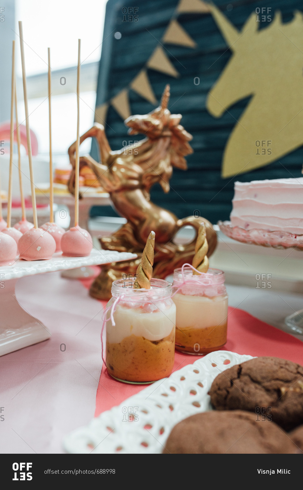 Unicorn themed sweet table with all kind of desserts and a golden unicorn sculpture
