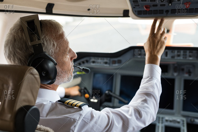 Male pilot pushing button in private cockpit