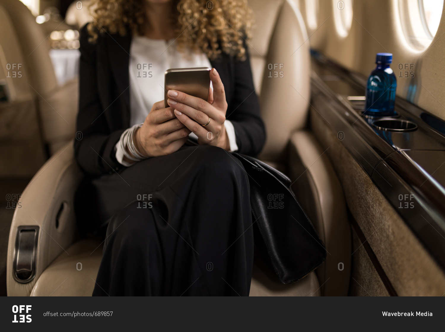 Mid section of businesswoman using mobile phone in private jet