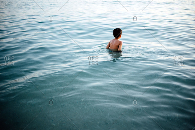Little boy wading through dark water alone