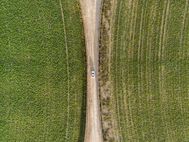 Aerial view of a car driving in between two agricultural circles in the middle of the Saih Al Salam Desert in Dubai, U.A.E.