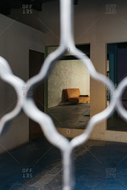 Framed view of empty furnished room through ornate gate pattern