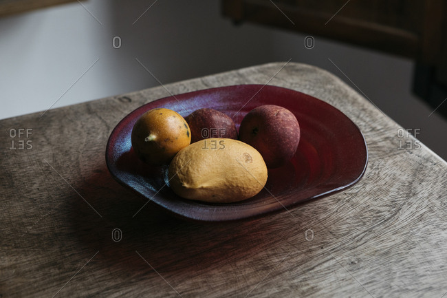 Ceramic bowl of fruit at corner of rustic wood table