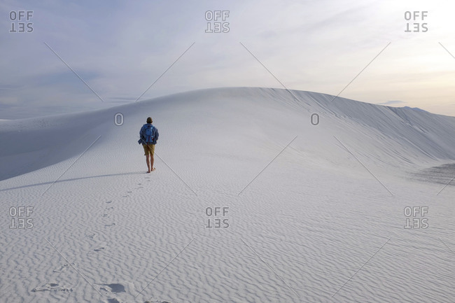 Man hiking alone at White Sands National Monument in New Mexico at sunset