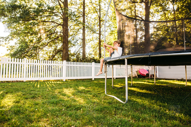 Young boy sitting on edge of trampoline taking a break