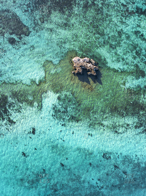 Aerial view of large coral head protruding from clear ocean waters off Exmouth, Australia